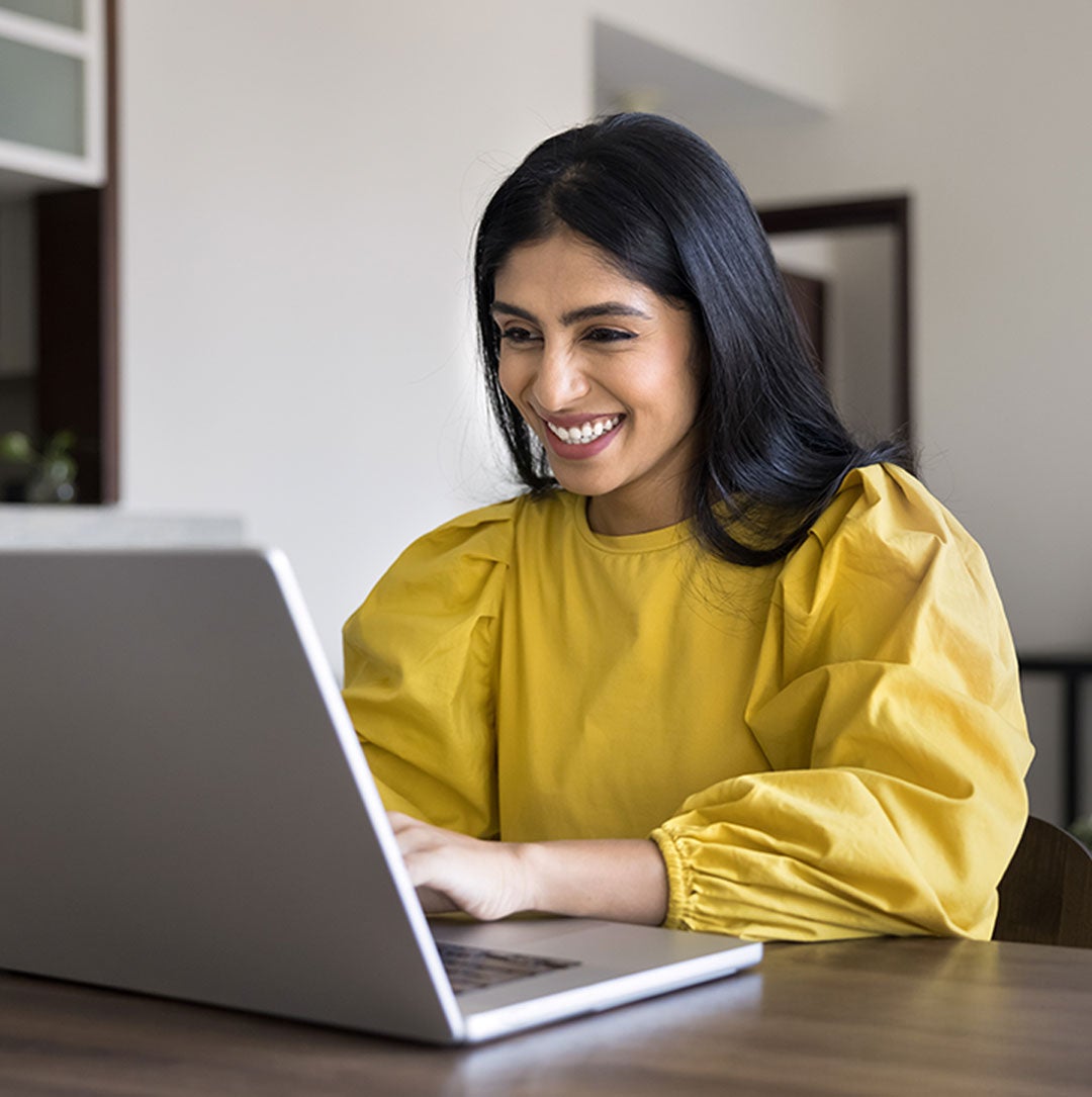 Image of a woman smiling taking an exam on the computer